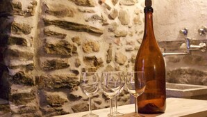 Un mur de pierre, un comptoir en bois et une bouteille avec des verres.