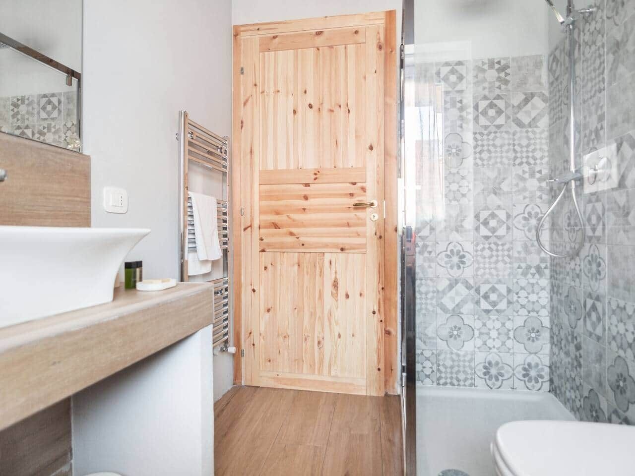 Un baño con puerta de madera, un lavamanos y baldosas estampadas.