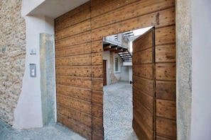 A wooden door leading to a stone building with a staircase visible in the background.