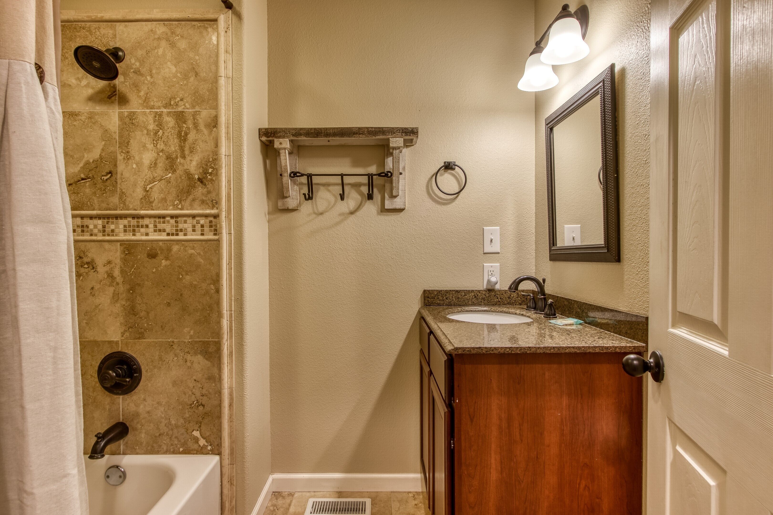 A bathroom with a shower, a sink, a mirror, and a towel rack.