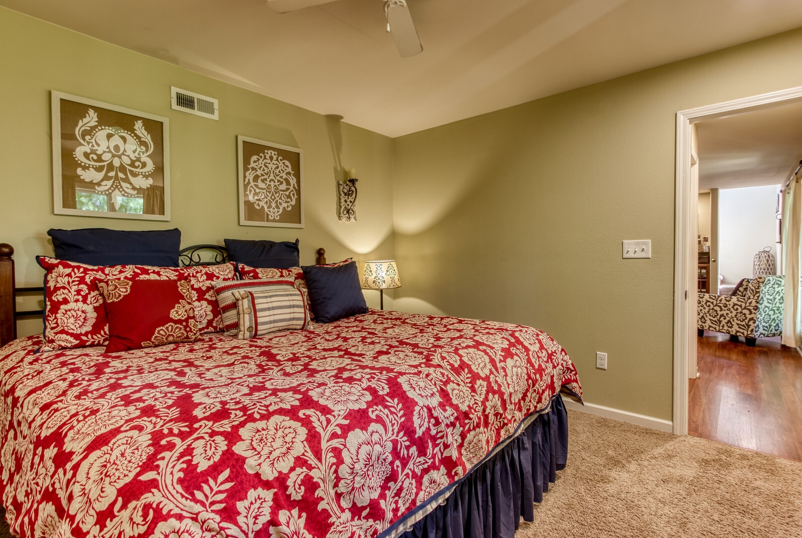 A bedroom with a large bed, two wall-mounted lamps, and a door leading to another room.