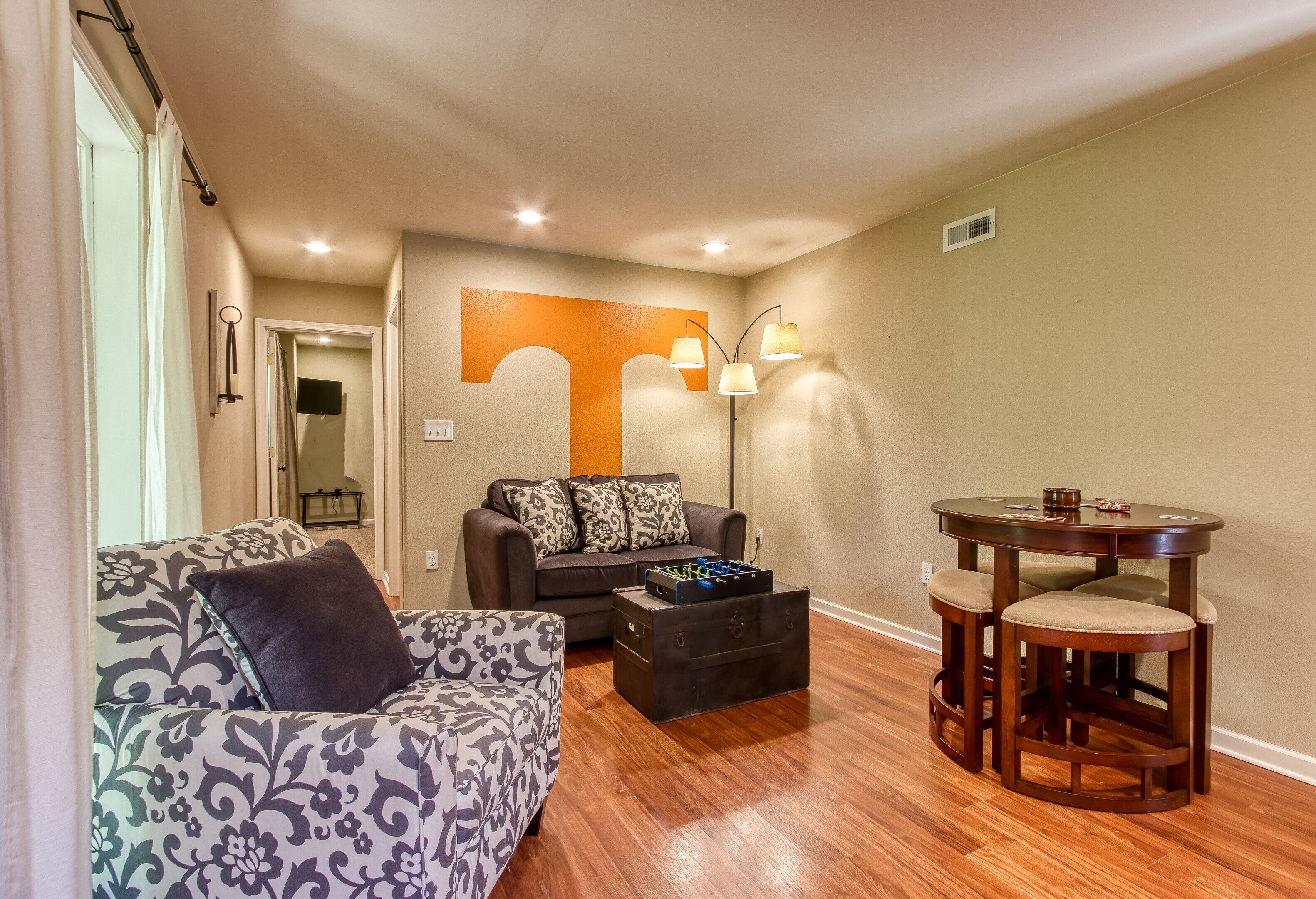 A living room with a sofa, a coffee table, and a round table with stools.