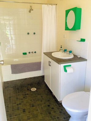 A bathroom with a bathtub, a sink, and a toilet. - Bermagui Bay Beach House - Bungalow. Pet friendly in the heart of town. (Bermagui)