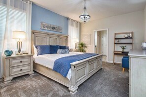A bedroom with a bed, nightstands, a desk, and a chandelier. - 8BR Storey Lake Villa | 6 King Beds, Theater, Game Room, Pool & Jacuzzi (Kissimmee)