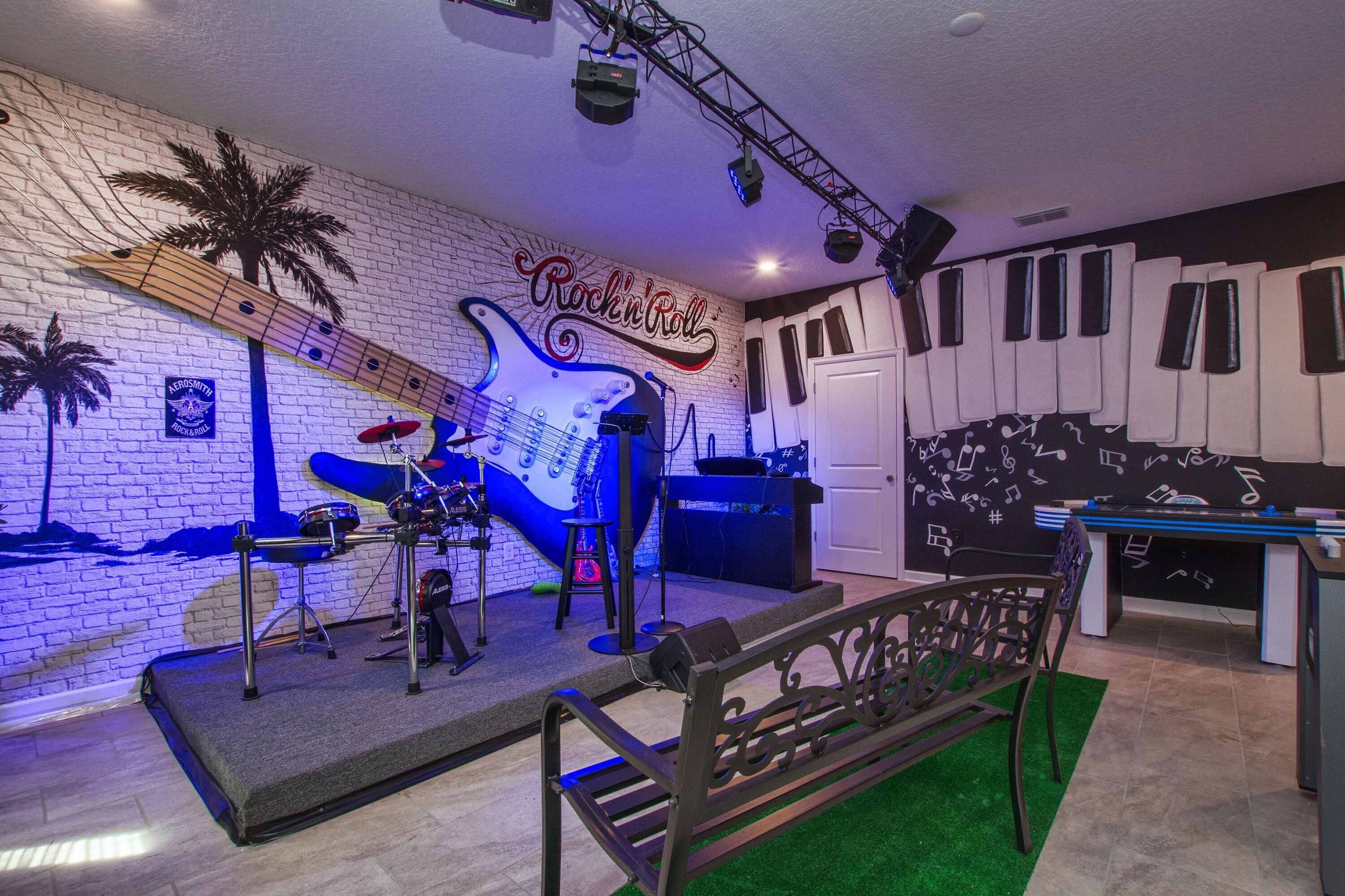 A stage with musical instruments and a 'Rockin' Roll' sign, a piano, and a seating area with a green carpet.