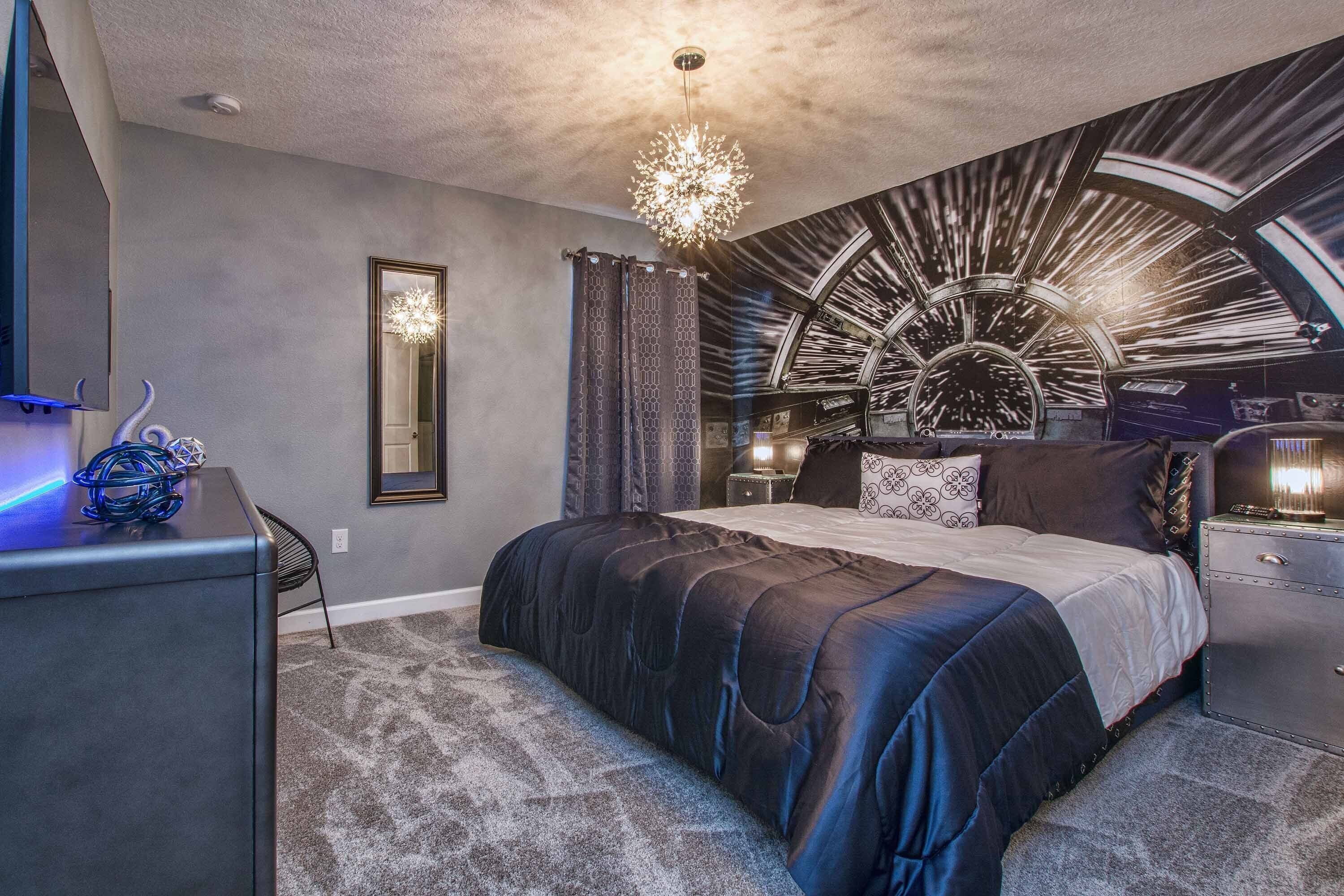 A modern bedroom with a large bed, a desk, and a unique ceiling design.