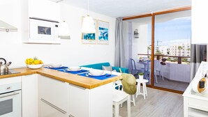 Eine moderne Küche mit weißen Schränken, einer Holz Arbeitsplatte und einem Essbereich mit einem blauen Sofa und weißen Stühlen.