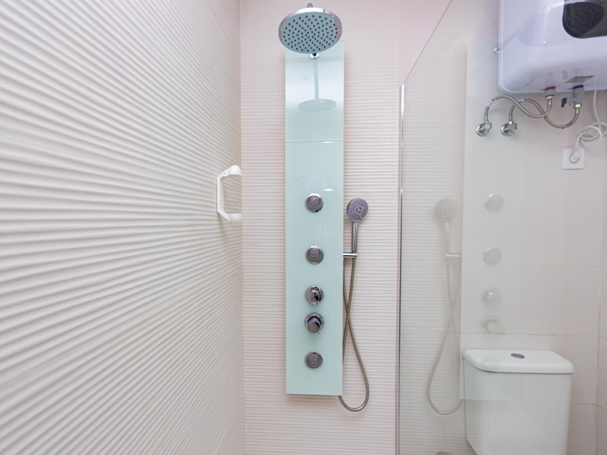 Un baño moderno con cabina de ducha de vidrio, inodoro y secador de manos.