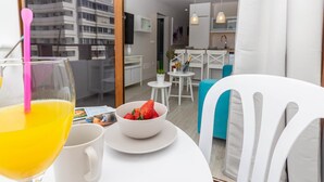 Ein modernes Hotelzimmer mit Balkon, einem Essbereich mit Tisch für zwei Personen und Blick auf die Stadt.