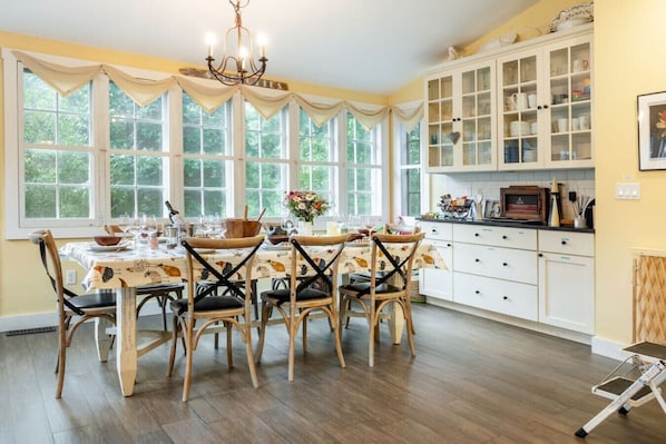 A dining area with a table set for four, surrounded by chairs, and a kitchen with cabinets and a countertop.