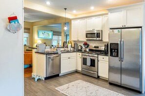 A modern kitchen with white cabinets, stainless steel appliances, and a small dining area.