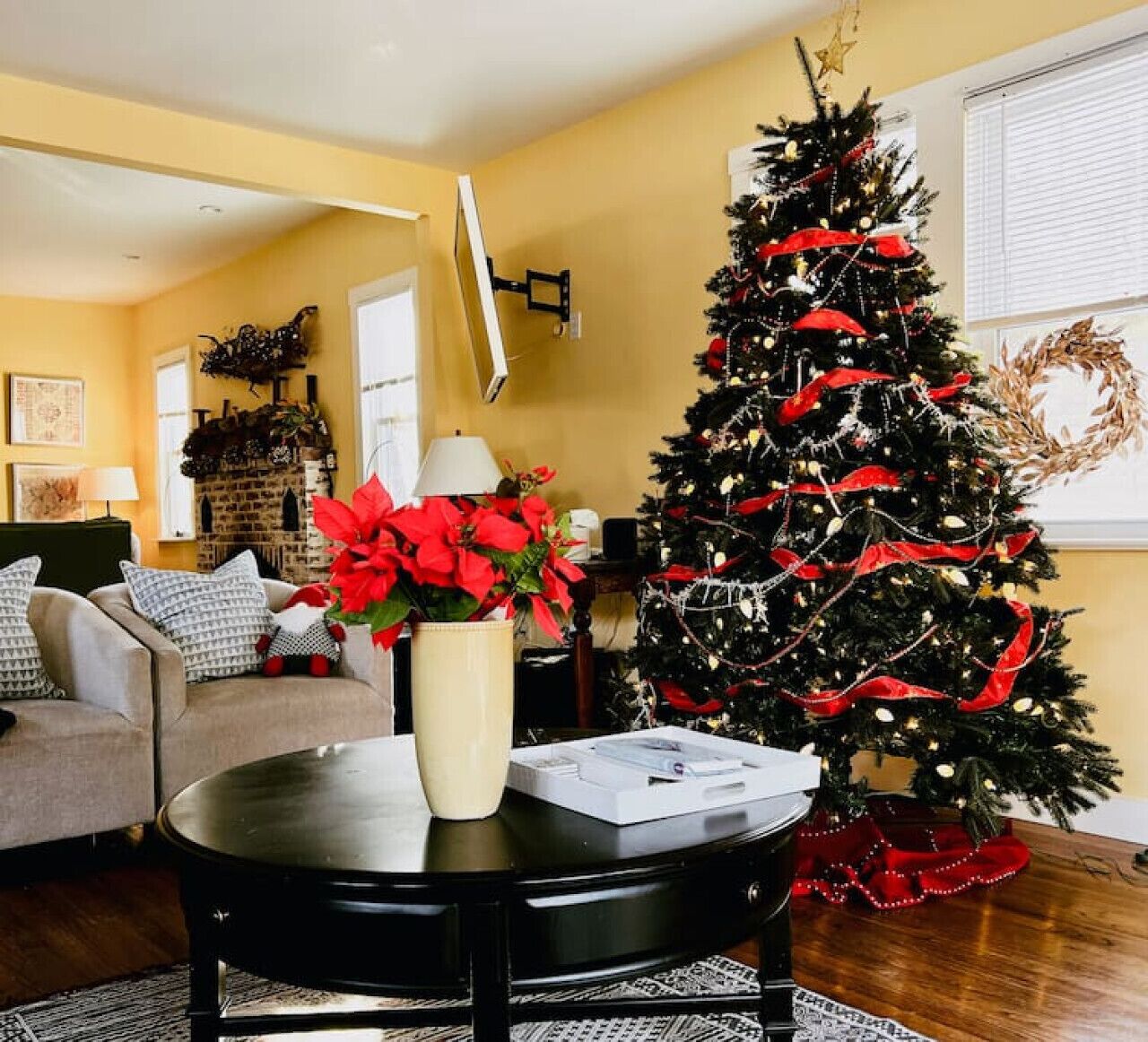 A living room with a Christmas tree, a sofa, a coffee table, and a fireplace.