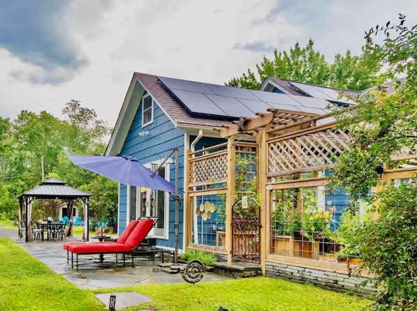 A blue house with a covered patio, a gazebo, and a garden. - Woodstock Farmhouse /Hot tub, Gardens,EV charger, Firepit, Pet/Family Friendly (Saugerties)