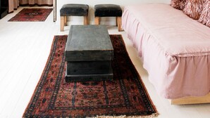Een slaapkamer met een bed, twee krukken, een vloerkleed en decoraties aan de muur.