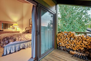 Una camera da letto con un letto, un comodino, una lampada e una finestra vista alberi.
