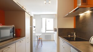 A modern kitchen with stainless steel appliances, a window, and a view of the adjacent room.