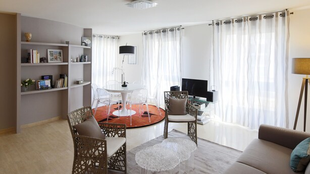 A living room with a round table, chairs, a sofa, a TV, and a bookshelf.