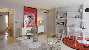 A modern living room with a round dining table, clear chairs, a white sofa, and a decorative rug.