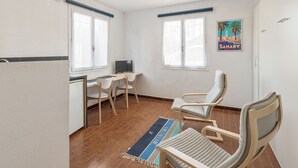 A compact room with a desk, two chairs, a small TV, and a poster on the wall. - Studio Bruscia - Welkeys (Six-Fours-les-Plages)
