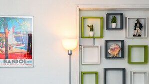 A wall with a framed poster, a wall-mounted lamp, and several empty picture frames. - Studio Varélia - Welkeys (Six-Fours-les-Plages)