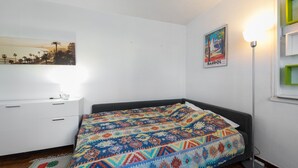 A bedroom with a bed, a nightstand, a lamp, and a poster on the wall. - Studio Varélia - Welkeys (Six-Fours-les-Plages)