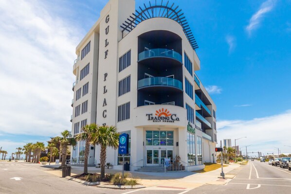 A multi-story hotel with balconies, a Trading Co. sign, and a parking sign. - Gulf Place Condos~Direct Beach Access~4BR (Gulf Shores)