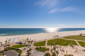 A beach resort with a sandy beach, palm trees, and a clear blue sky. - Gulf Place Condos~Direct Beach Access~4BR (Gulf Shores)