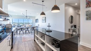 Une cuisine moderne dotée d’un îlot central, de luminaires suspendus et offrant une vue sur la ville.