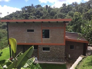 Situated in a lush environment, this two-story building offers a simple, functional design with a flat roof and brick facade.