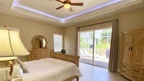 Un dormitorio con cama, cómoda, tocador y ventilador de techo.