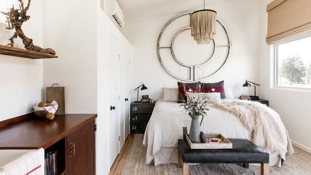 Un dormitorio con cama, mesitas de noche, cómoda, lámpara colgante y ventana con vistas.