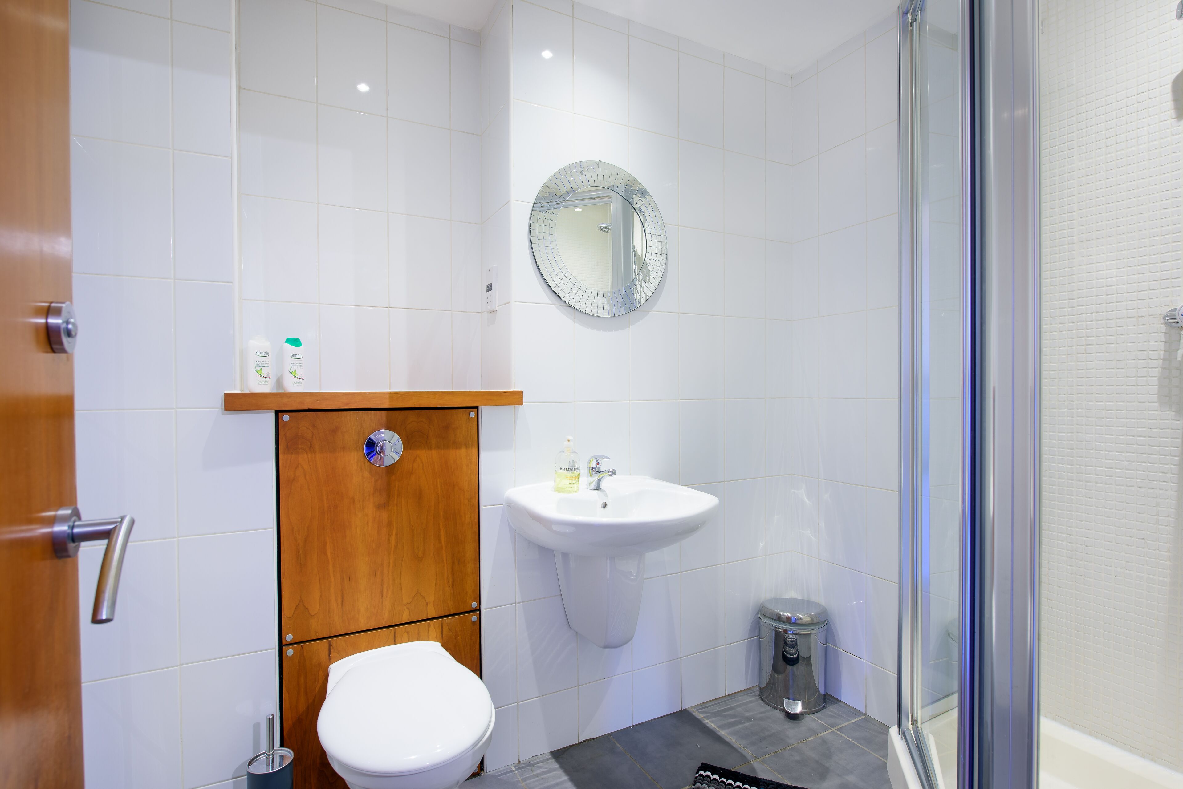 A modern bathroom with a white toilet, a sink with a mirror above it, and a glass shower enclosure.