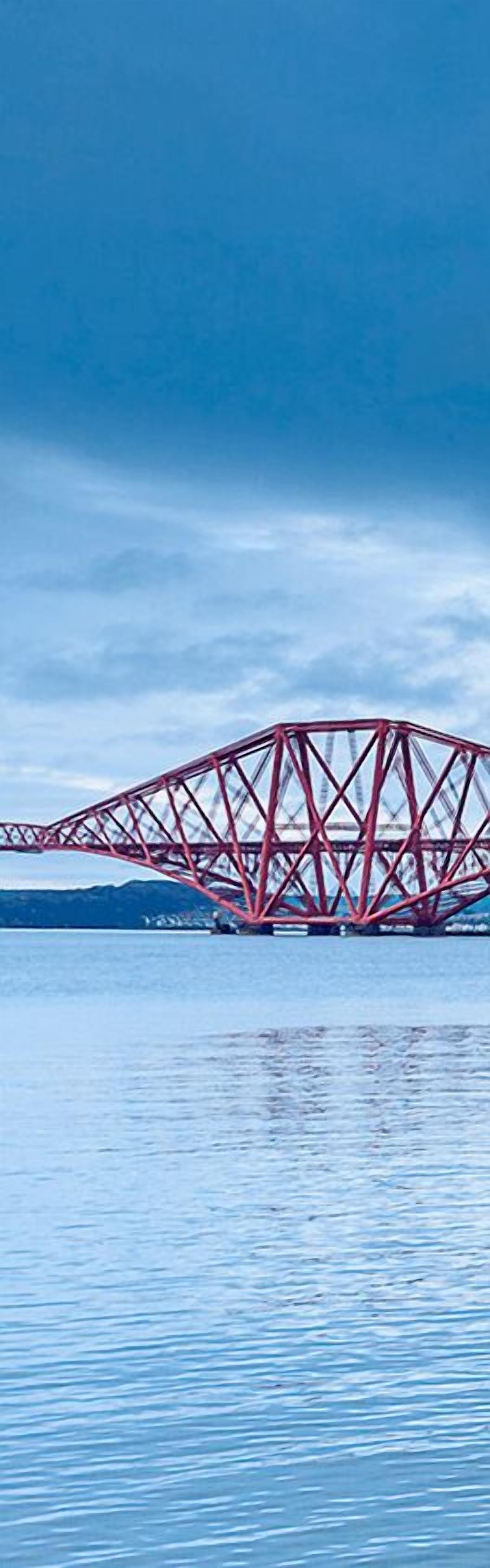 A red steel bridge over calm water.