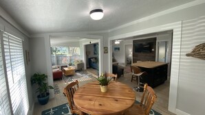 A spacious living area with a wooden dining table, comfortable seating, and a large TV. - Rock Ridge I. Private and close to everything. (Vero Beach)