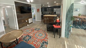 A modern kitchen with stainless steel appliances, a dining area with a round table and chairs, and a patterned rug. - Rock Ridge I. Private and close to everything. (Vero Beach)