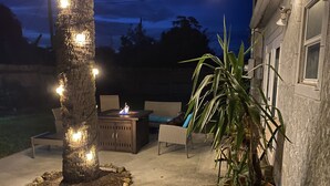 An outdoor patio area with a fire pit, seating, and a potted plant. - Rock Ridge I. Private and close to everything. (Vero Beach)