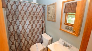 A bathroom with a shower curtain, toilet, sink, and a framed picture on the wall.
