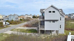 A two-story residential building with a balcony, located in a suburban neighborhood with houses in the background.