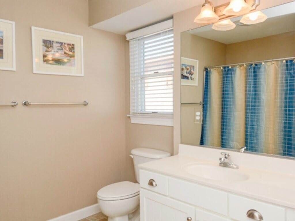 A bathroom with a toilet, sink, and a large mirror.