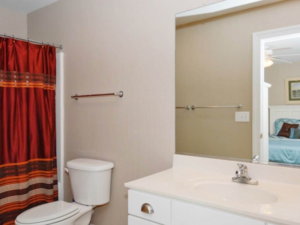 Un bany amb un vàter blanc, un lavabo blanc i un mirall sobre el lavabo.