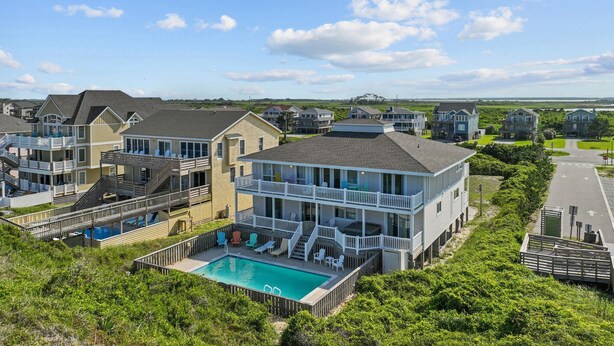 A coastal residential area with multiple two-story houses featuring balconies, a swimming pool, and a view of the ocean.
