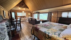A cozy tent-style room with a bed, a sofa, a dining table, and a piano. - The Rose Den - Romantic Mountain Cabin with Views! (Estes Park)