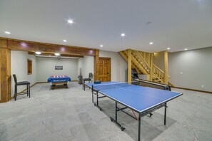 Een biljartkamer met een pooltafel, stoelen en een trap.