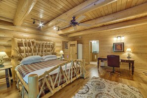 A log cabin bedroom with a bed, a desk, and a chair.
