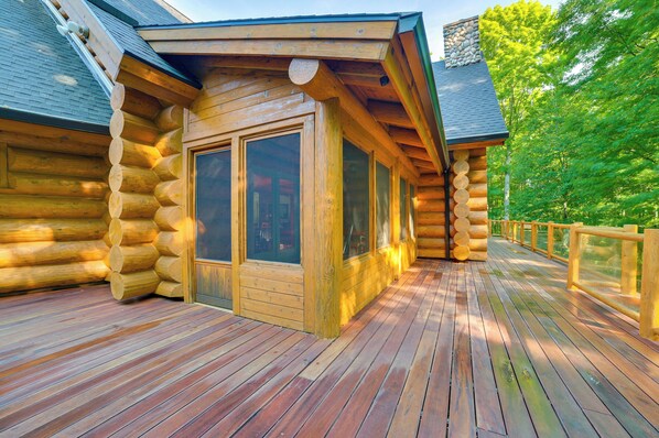 Una cabaña de troncos con terraza de madera y ventanas amplias.