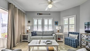A living room with a sofa, coffee table, and armchairs, a ceiling fan, and a TV. - Walk to Destin Beach: Coastal Condo w/ Pool Access (Destin)