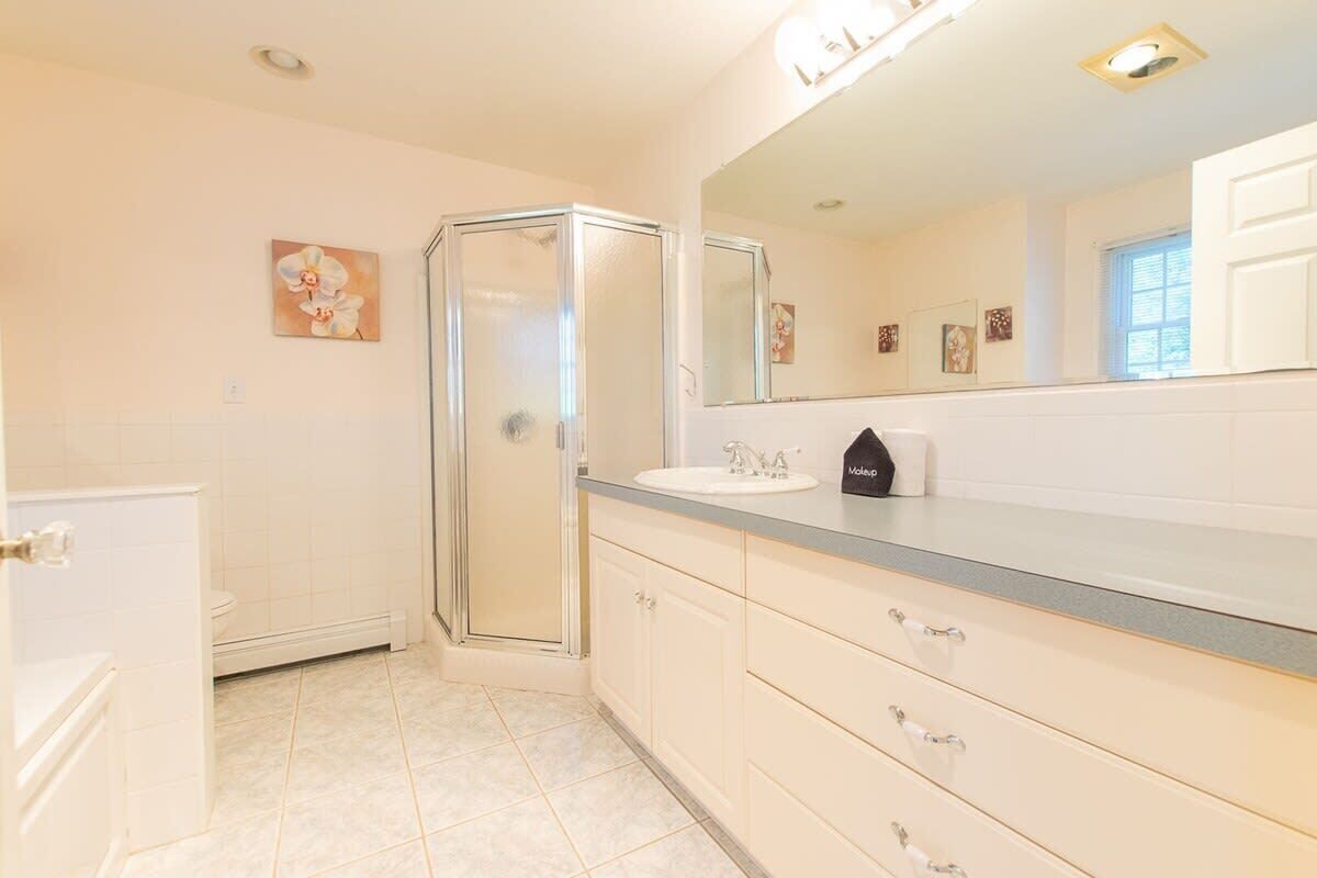 Ein Badezimmer mit Glasdusche, Waschbecken mit Spiegel und Toilette.