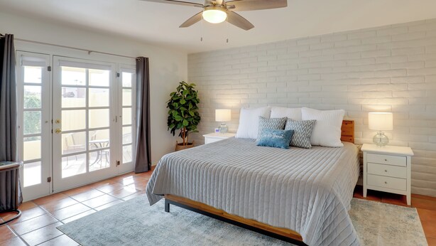 A bedroom with a bed, nightstands, a ceiling fan, a potted plant, and a view through a sliding glass door. - Tucson Townhome w/ Private Patio & Mtn Views! (Tucson)