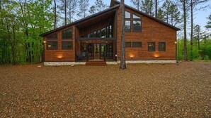 Une maison en rondins moderne, dotée d’une grande véranda à l’avant, de nombreuses fenêtres et de fondations en pierre.
