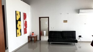 A modern living room with a black sofa, a small wooden table, and artwork on the walls. - Casa Vacacional San Andres (San Andrés)